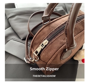 Detailaufnahme der braunen Wildledertasche mit glattem Metallreißverschluss und Ledergriff