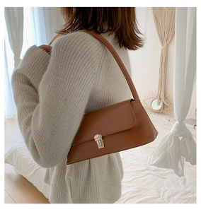 Détail d'un sac baguette en cuir marron avec boucle en métal doré et finition lisse élégante