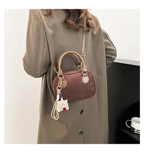 Detail of vintage brown suede bowling bag worn with a beige coat and plush star charm