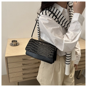 Détail du sac baguette noir gaufré crocodile avec des finitions en métal doré clair