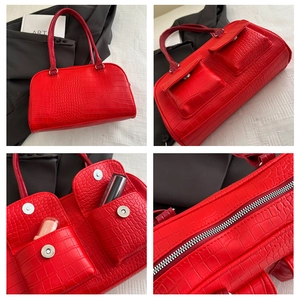 Macro detail of red crocodile texture handbag with dual front pockets and silver zipper