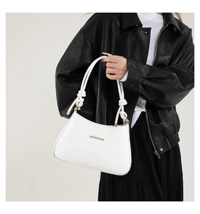 Détail d'un sac blanc avec bandoulière à nœuds et boucle métallique dorée élégante