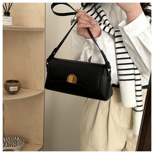 Détail du sac baguette en cuir noir avec boucle dorée et bandoulière réglable pour femme