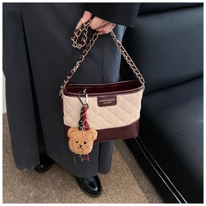 Close-up of quilted contrast chain bag featuring a plush bear charm and metallic hardware