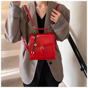 Dettaglio della borsa tote rossa in pelle cerata con patta vintage e ciondolo a campana
