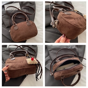 Detailansicht der braunen Wildledertasche mit Plüsch-Anhänger und Innenraum-Details