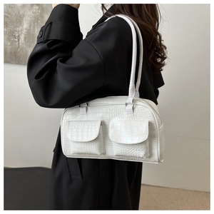 Detail of white crocodile texture shoulder bag with dual front flap pockets on a model