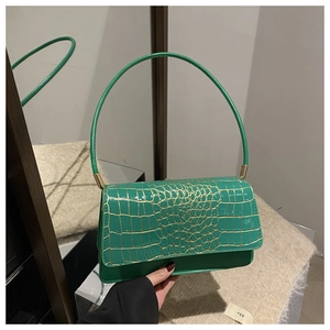 Detail shot of green crocodile pattern texture and circular handle on vintage shoulder bag