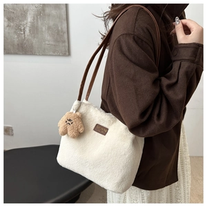 Detail of white plush tote bag with brown leather handles and a cute bear pendant