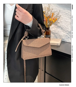 Detail of woven straw bag with knot handle and adjustable strap on a minimalist model