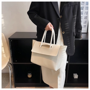 Detail of minimalist cream leather tote bag with unique cylindrical handle and matte finish