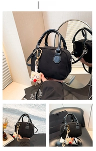 Detail of black velvet pillow bag with plush beige keychain and smooth top handles