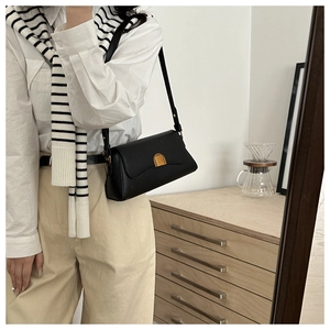 Sac sous le bras noir chic avec boucle dorée présenté sur un mannequin de mode