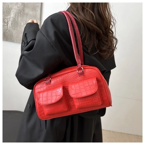 Close-up of red crocodile embossed handbag with silver metal rings and front pockets