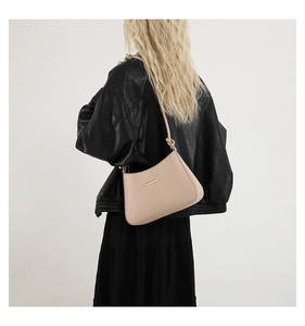 Modèle portant un sac à bandoulière en cuir PU beige avec garniture dorée et nœud décoratif
