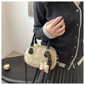 Detail of vintage beige bowling bag with textured embroidery and cute plush charm pendant