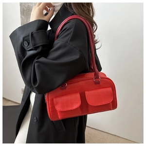 Model wearing a red crocodile pattern shoulder bag with a black coat on white background