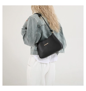Détail du sac sous l'aisselle noir minimaliste avec boucle dorée et bandoulière nouée