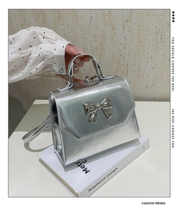 Detail of silver metallic handbag featuring a large 3D bow and reflective mirror finish