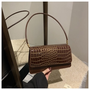 Detailed close-up of glossy brown crocodile pattern finish and gold metal hardware on handbag