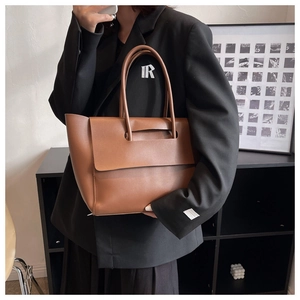 Detail view of brown leather tote bag showing handle construction and matte texture