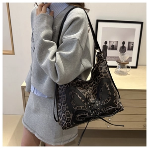 Detail of leopard print tote bag with black bow leather patch and lace-up design