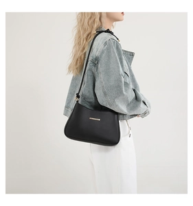 Close-up of black PU leather shoulder bag featuring minimalist gold metal bar accent