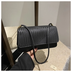 Detail of black woven texture lid and smooth faux leather surface on women shoulder bag