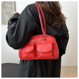 Detail of red faux-crocodile leather shoulder bag with functional double front pockets