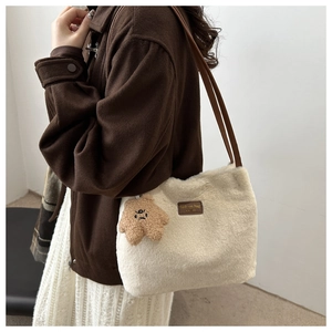 Détail du cabas en peluche avec pendentif étoile marron et étiquette cuir sur texture