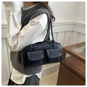 Detail of dark blue faux crocodile leather bag featuring dual front flap pockets
