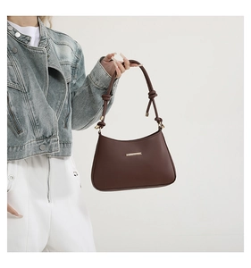 Détail du sac à bandoulière en cuir marron foncé avec finitions dorées et nœud élégant