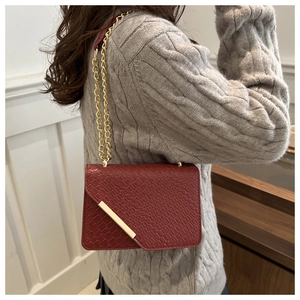 Detail of red crocodile texture PU leather shoulder bag with golden chain and clasp