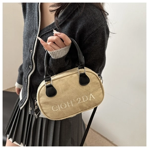 Detail of the stitched CIOH'2DA lettering on the beige fabric handbag with black handles