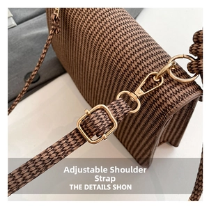 Detail view of the adjustable woven shoulder strap with gold metal hardware on brown bag