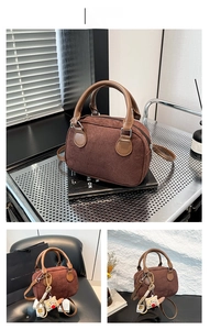 Detail view of coffee-colored frosted suede bowling bag with contrast leather handles