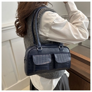Close-up of a navy blue crocodile pattern tote bag shown on a model's shoulder