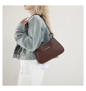 Détail du sac sous le bras en cuir marron avec garniture dorée et bandoulière nouée
