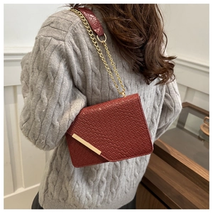 Détail du sac à bandoulière bordeaux à texture crocodile avec chaîne dorée élégante