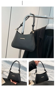Detail of black leather underarm bag with gold hardware and hand-knotted strap