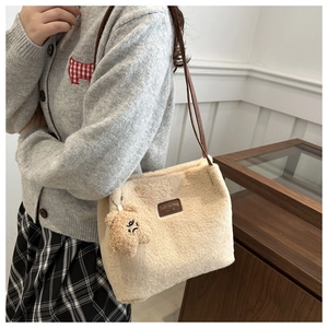 Détail du cabas en peluche beige avec anses en cuir et petit pendentif ours mignon