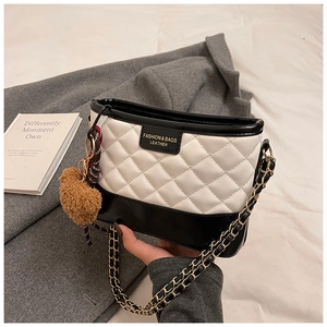 Detail of quilted white and black crossbody bag with chain strap and fuzzy charm