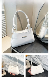 Close-up of white faux leather shoulder bag featuring gold hardware and knot handle detail