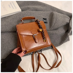 Dettaglio dello zaino vintage in pelle cerata marrone con fibbia e ornamento a campana