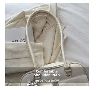 Detailaufnahme der cremefarbenen Leder-Schultertasche mit silbernem Schleifenanhänger