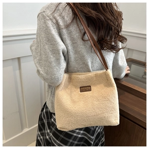 Detailed close-up of cream faux fur tote bag featuring a leather patch and brown strap