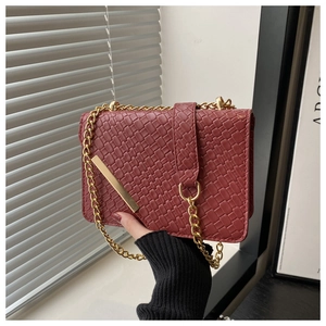 Detail of burgundy woven texture small square bag with gold chain strap and metal clasp