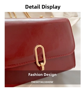 Close-up of red glossy leather bag with gold oval buckle and metallic chain strap