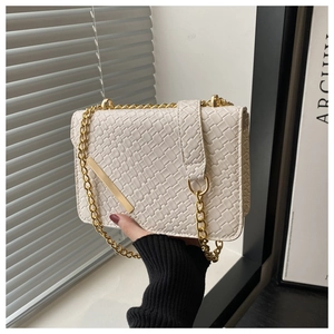 Detail of white woven texture flap bag with gold chain strap and metallic accents