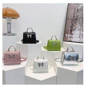 Five elegant handbags with metal bow details displayed on stylish white pedestals